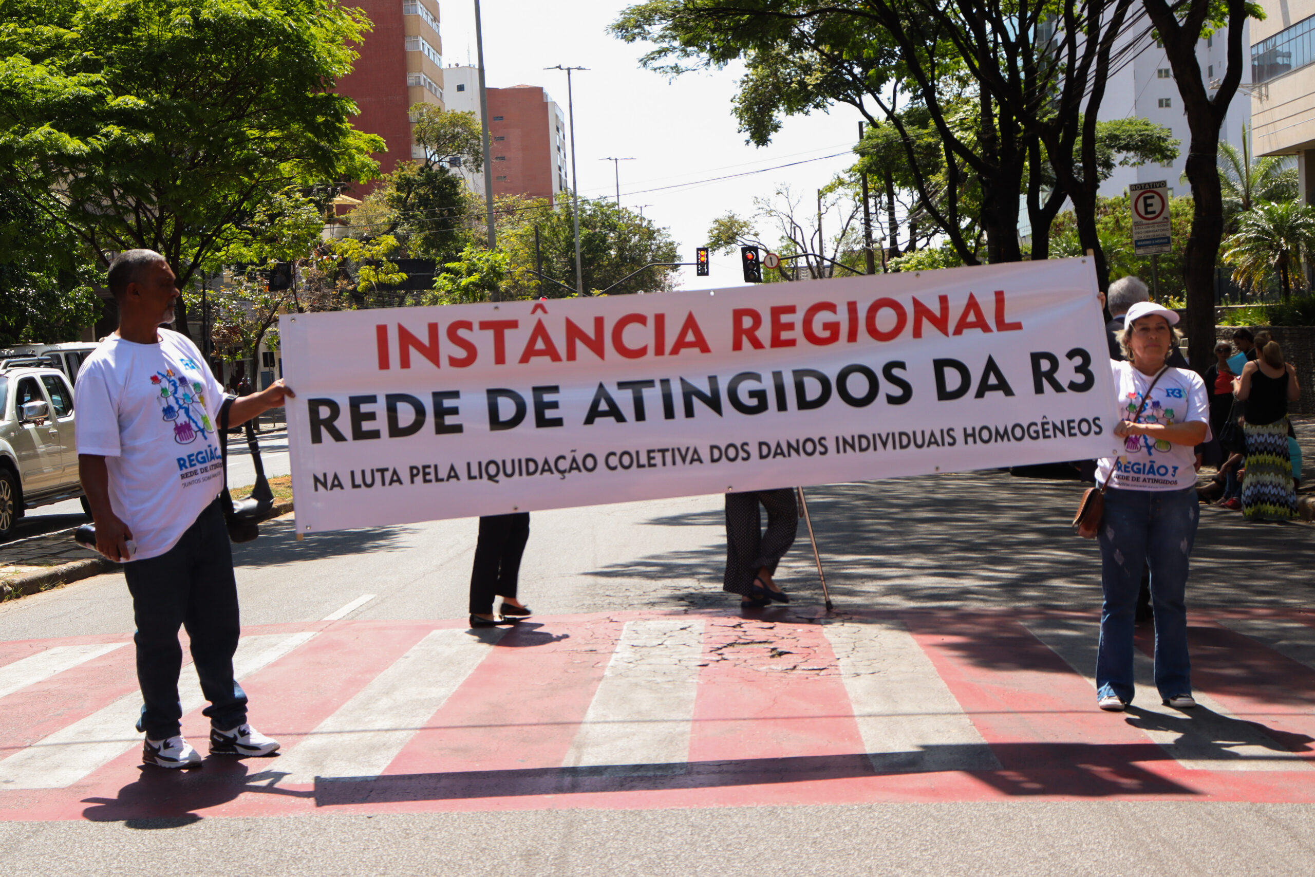 pessoas atingidas com faixa manifestando pela liquidação coletiva dos danos individuais homogêneos